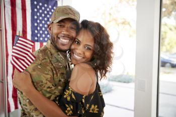 Millennial black soldier and his wife embracing at home and smiling to camera,close up