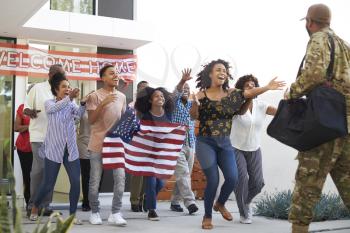 Three generation black family running out of house to welcome soldier returning home, low angle view
