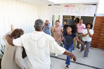 Black family running to welcome grandparents for a surprise family party