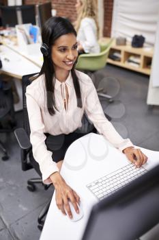 Female Customer Services Agent Working At Desk In Call Center