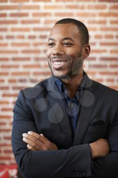 Businessman Standing Against Brick Wall In Modern Office