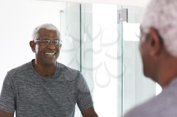 Smiling Senior Man Looking At Reflection In Bathroom Mirror Wearing Pajamas