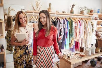 Portrait Of Two Female Sales Assistants With Digital Tablet Working In Clothing And Gift Store