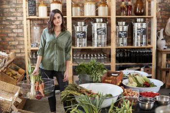 Portrait Of Woman Buying Fresh Fruit And Vegetables In Sustainable Plastic Free Grocery Store