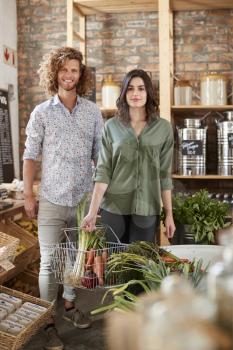 Portrait Of Couple Buying Fresh Fruit And Vegetables In Sustainable Plastic Free Grocery Store
