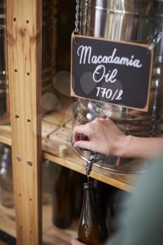 Man Filling Container With Macadamia Oil In Sustainable Plastic Free Grocery Store