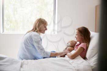Mother Visiting Daughter Lying In Bed In Hospital Ward