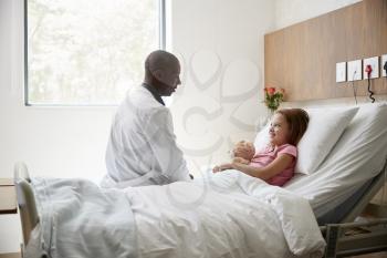 Male Doctor Visiting Girl Lying In Hospital Bed Hugging Teddy Bear