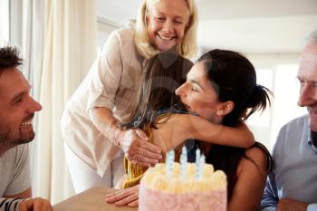 Mid adult woman embracing her daughter after blowing out candles on birthday cake, close up