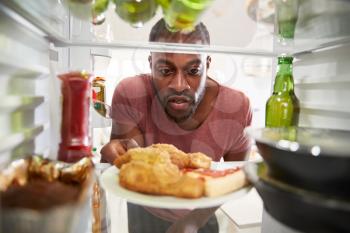 View Looking Out From Inside Of Refrigerator Filled With Unhealthy Takeaway Food As Man Opens Door