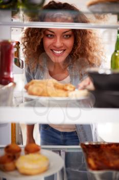 View Looking Out From Inside Of Refrigerator Filled With Takeaway Food As Woman Opens Door