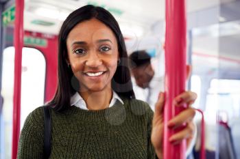 Portrait Of Smiling Female Passenger Standing By Doors In Train
