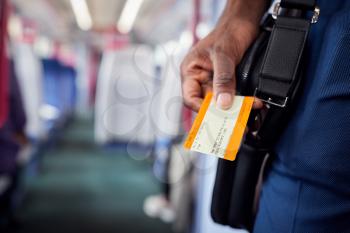 Close Up Of Businessman Standing In Train Commuting To Work Holding Ticket