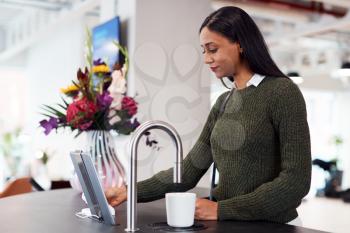 Businesswoman Getting Hot Drink From Automated Dispenser In Office