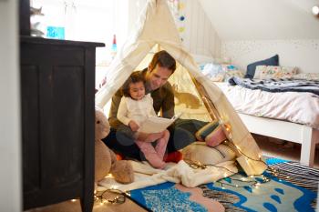 Single Father Reading With Daughter In Den In Bedroom At Home
