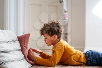 Boy Lying On Floor Of Bedroom Spending Too Much Time Using Mobile Phone