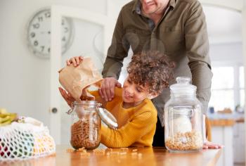 Father Helping Son To Refill Food Containers At Home Using Zero Waste Packaging