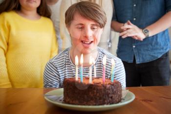 Young Downs Syndrome Man Celebrating Birthday At Home With Cake
