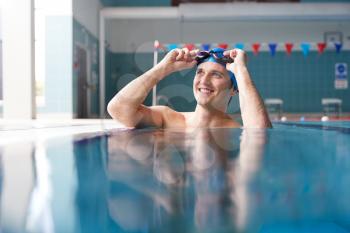 Male Swimmer Wearing Hat And Goggles Training In Swimming Pool