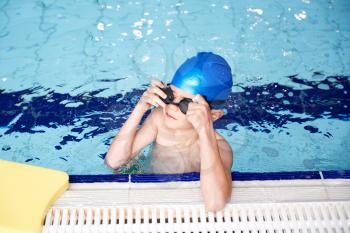 Boy With Float Resting On Edge Of Swimming Pool During Lesson