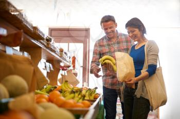 Mature Couple With Paper Bag Buying Fresh Bananas In Organic Farm Shop Together