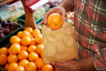 Close Up Of Male Customer With Paper Bag Buying Fresh Oranges In Organic Farm Shop