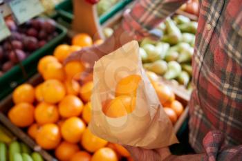 Close Up Of Male Customer With Paper Bag Buying Fresh Oranges In Organic Farm Shop