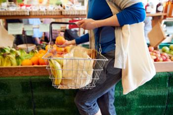 Close Up Of Female Customer With Shopping Basket Buying Fresh Produce In Organic Farm Shop