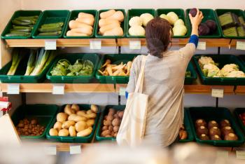 Rear View Of Female Customer Choosing Fresh Produce In Organic Farm Shop
