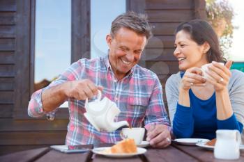 Portrait Of Mature Couple Sitting On Bench In Cafe Whilst Visiting Garden Center