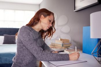 Female College Student In Shared House Bedroom Studying Sitting At Desk