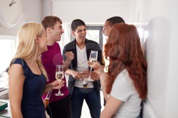 Group Of College Students In Shared House Kitchen Hanging Out And Drinking Together