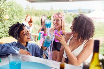 Female Friends Buying Drinks From Bar At Music Festival Making A Toast