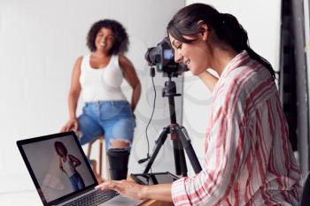 Female Photographer In Digital Studio Shooting Images On Camera Tethered To Laptop Computer