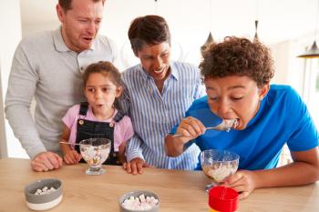 Family In Kitchen With Children Making And Eating Ice Cream Desserts
