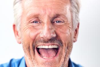 Close Up Studio Shot Of Mature Man Against White Background Laughing At Camera
