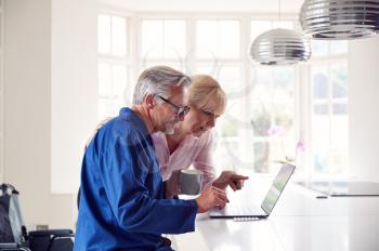 Mature Couple With Man In Wheelchair Looking Up Information About Medication Online Using Laptop