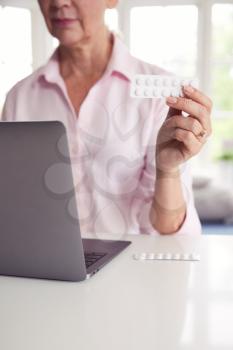 Close Up Of Mature Woman At Home Looking Up Information About Medication Online Using Laptop