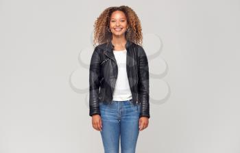 Three Quarter Length Studio Shot Of Happy Young Woman Wearing Leather Jacket Smiling At Camera