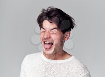 Head And Shoulders Studio Shot Of Man Pulling Faces And Smiling At Camera
