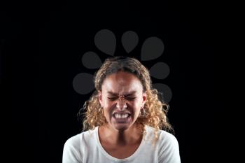 Studio Portrait Of Angry Woman Shouting At Camera Against Black Background
