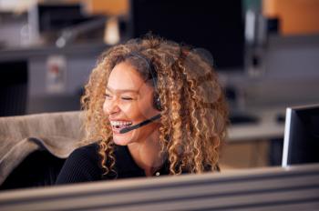 Laughing Businesswoman Wearing Telephone Headset Talking To Caller In Customer Services Department