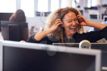 Laughing Businesswoman Wearing Telephone Headset Talking To Caller In Customer Services Department
