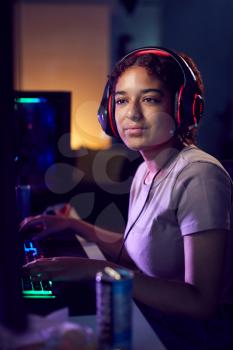 Teenage Girl With Caffeine Energy Drink Gaming At Home Using Dual Computer Screens At Night