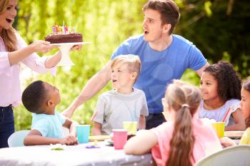 Parents And Son Celebrating Birthday With Friends Having Party In Garden At Home