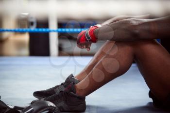 Close Up Of Tired Male Boxer Sitting In Boxing Ring In Gym After Training Session