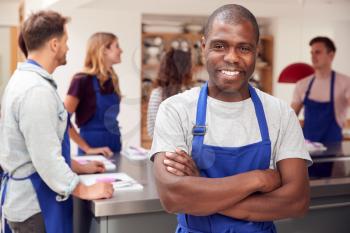 Portrait Of Smiling Man Wearing Apron Taking Part In Cookery Class In Kitchen