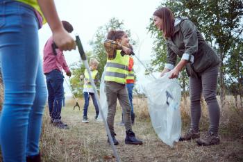 Adult Team Leaders With Group Of Children At Outdoor Activity Camp Collecting Litter Together