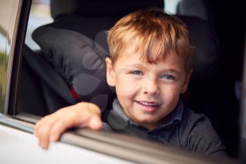Portrait Of Young Boy Sitting In Child Safety Seat On Car Journey Looking Out Of Window