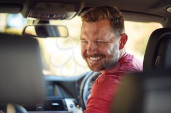Father Turning Round To Talk To Children In Back Seat On Car Journey